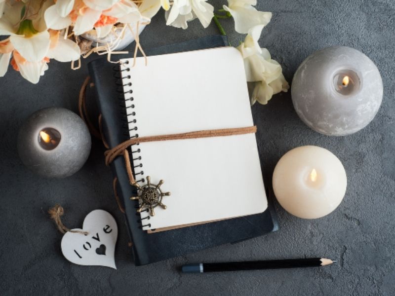 Flat lay of a journal with candles, flowers, and the word "love" to represent peaceful journaling for mental health