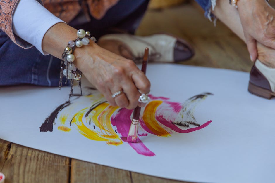 Top art business terms and conditions image of woman painting expressive brushstrokes on paper, representing creative process and art business terms and conditions. An artist paints abstract, colorful strokes on paper with a brush, showcasing her creativity.